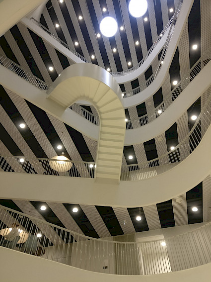 Yleiskuva Metropolia Ammattikorkeakoulun uuden Myllypuron kampuksen avarista sisätiloista ja valkoisista portaista.