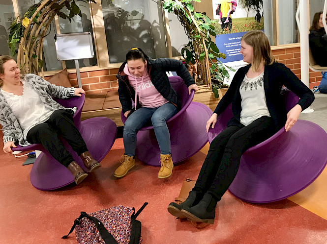 Kuvassa kolme Metropolia My Active Campus -hankkeen työntekijää. Henkilöt istuvat ja tasapainoilevat suurilla keikkuvilla tuoleilla.