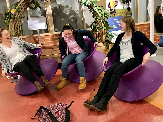 In the picture there is three persons from My Active Campus project. They are sitting and balancing with activation chairs. They are happy.