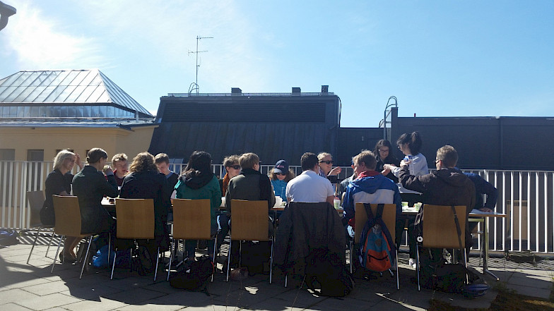 Students sitting around a table on the roof terrace of the Language Centre.