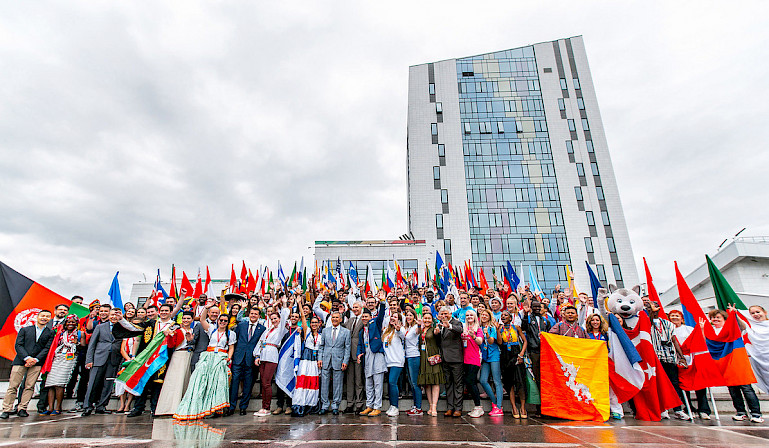 Volunteers from different countries at FISU’s event. Some are wearing national dress and holding flags of different countries.